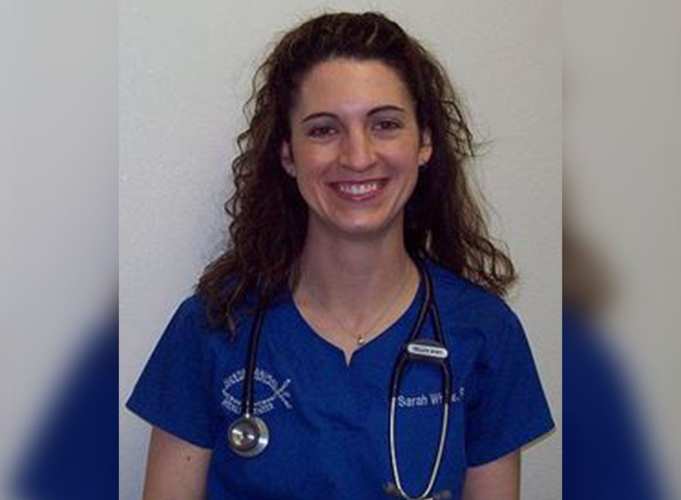 Smiling woman in blue scrubs with a stethoscope around her neck.