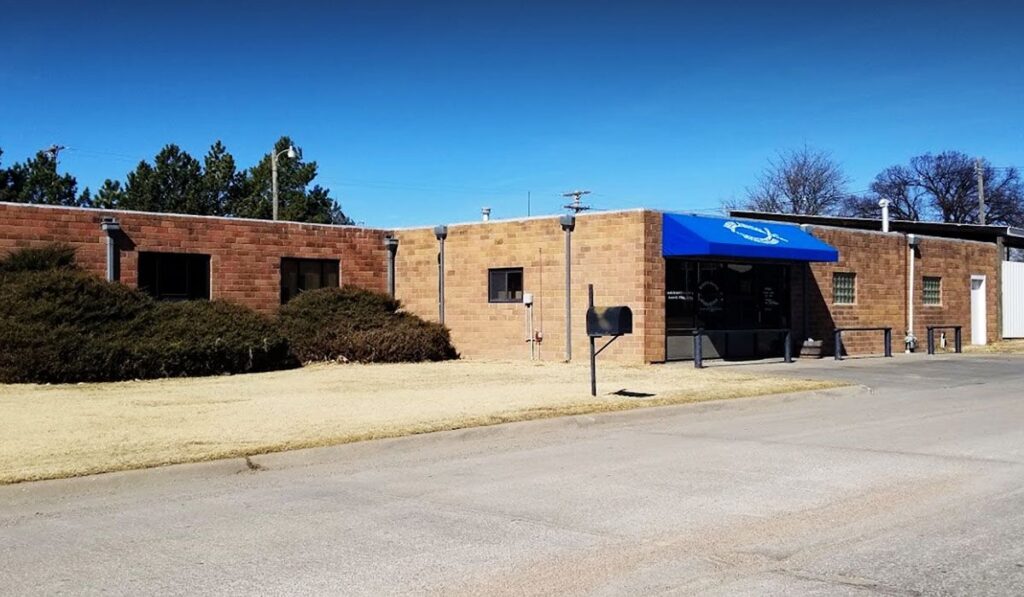 A small commercial building with a blue awning and brick exterior under a clear sky.