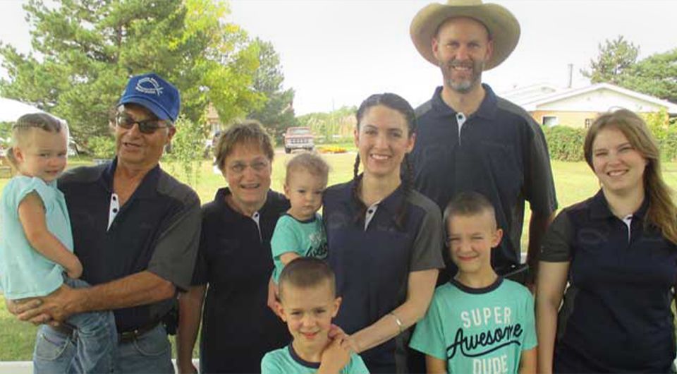 A multi-generational family of nine smiling outdoors.